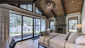 Un dormitorio amplio con una cama grande, una chimenea y vistas al exterior.