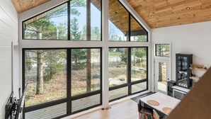 Eine moderne Küche mit großen Fenstern, Holzboden und Blick ins Freie.