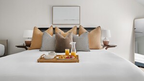 A neatly made bed with a tray of breakfast, including croissants, strawberries, and orange juice. There are two bedside lamps and a framed picture on the wall. - 1 Block to Historic King St | The Place to Be (Charleston)