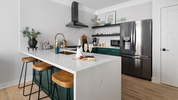 A modern kitchen with a central island, bar stools, a stainless steel refrigerator, and a herringbone-patterned backsplash. - 1 Block to Historic King St | The Place to Be (Charleston)
