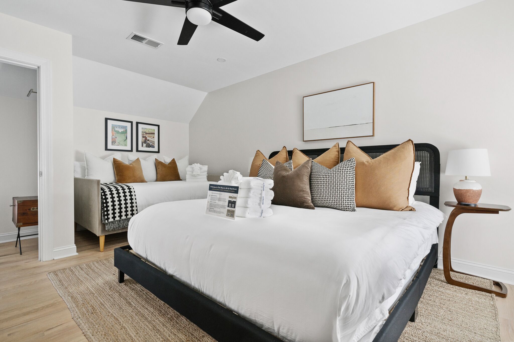 A modern bedroom with a large bed, a ceiling fan, and a bedside table with a lamp.
