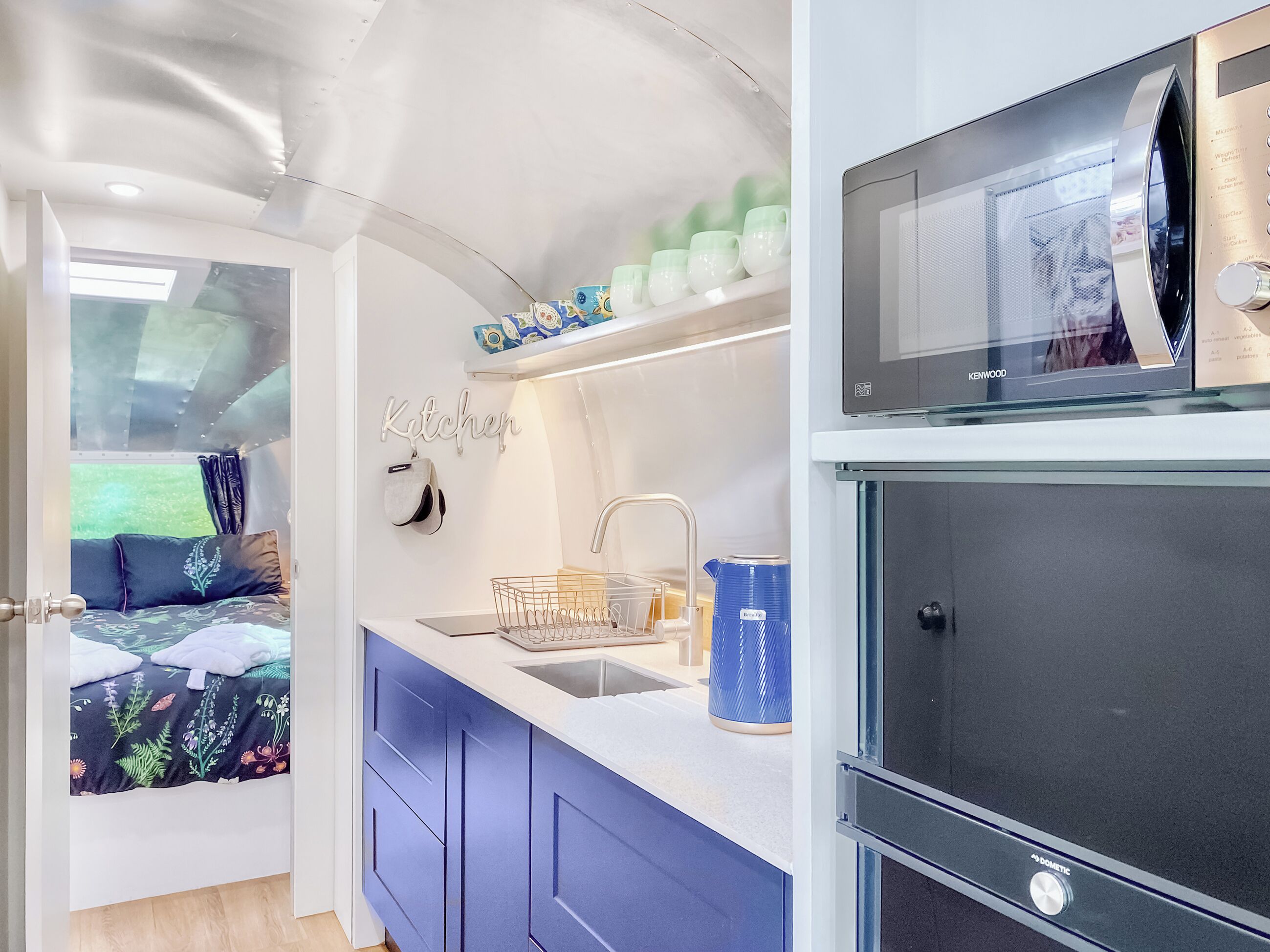 A compact kitchen with a sink, a kettle, and a microwave.