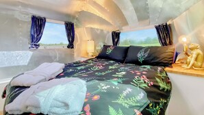 Une chambre confortable avec un lit, des oreillers, une lampe de chevet et une table de nuit.
