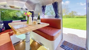 Un intérieur chaleureux avec une table en bois, un banc rembourré et une fenêtre donnant sur un champ verdoyant.