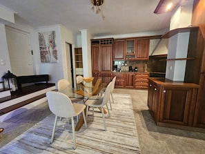 A modern kitchen with wooden cabinets, a glass dining table, and a bench.