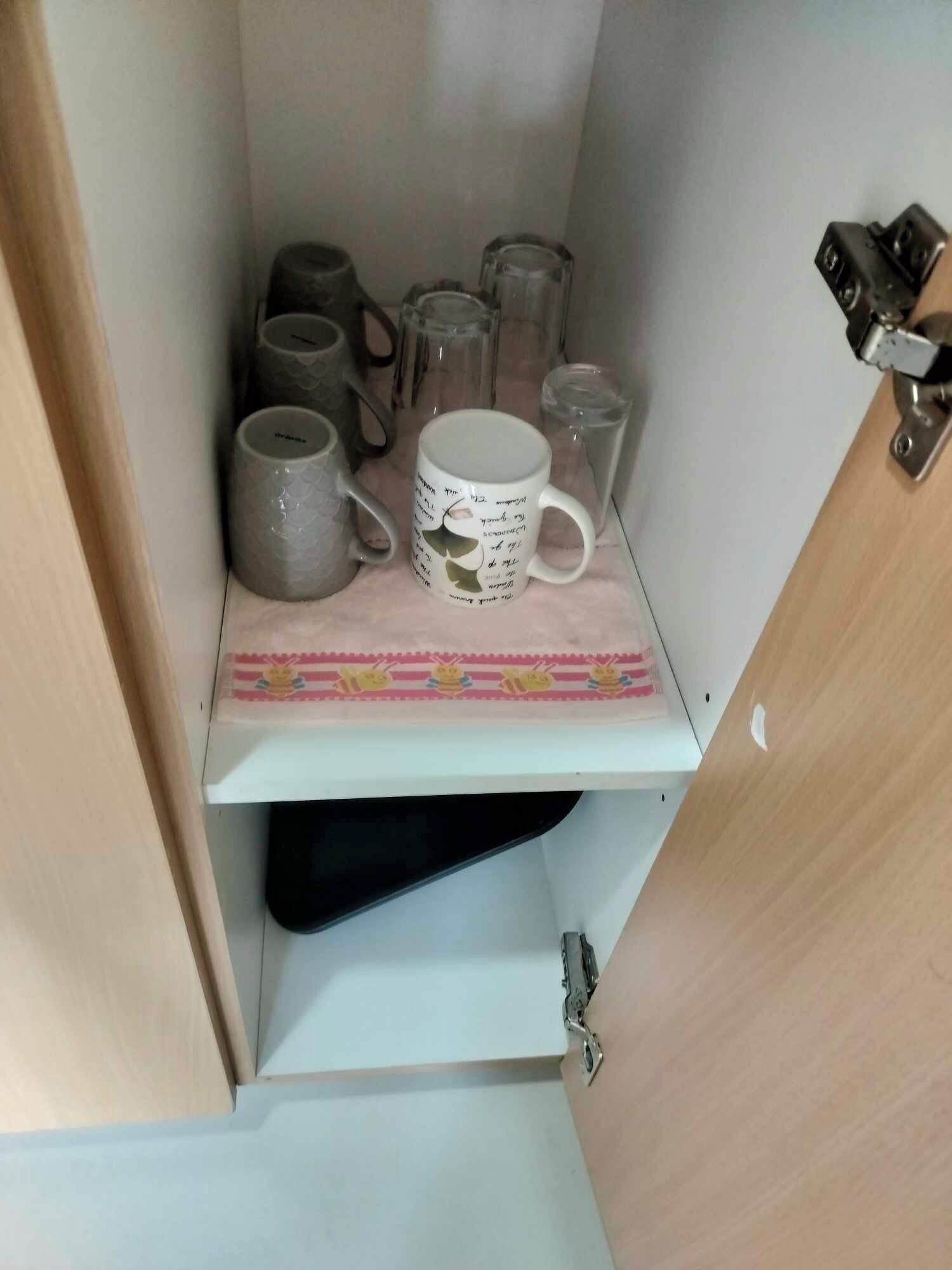 Un área de almacenamiento con estantes que contienen varias tazas y un pequeño objeto decorativo.