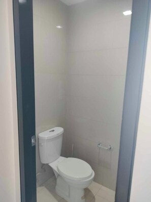 A small, enclosed bathroom with a toilet and a shower stall. - Luxury 1BR 55sqm 1 Pacific MactanNewtown (Lapu-Lapu)