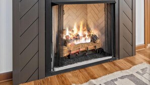 Ein Kamin mit modernem Design, darüber ein angebauter Fernseher und ein Holzboden.