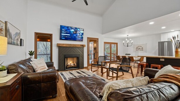 A modern living room with a fireplace, leather furniture, and a television mounted on the wall.