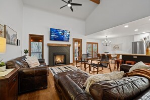 Ein modernes Wohnzimmer mit Kamin, Ledermöbeln und einem an der Wand montierten Fernseher.