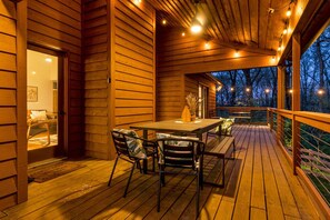 A wooden deck with a table and chairs, surrounded by wooden walls and a railing.