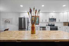 Eine moderne Küche mit weißen Schränken, Edelstahlgeräten und einer Holztheke mit einem Stäbchen-Blumengesteck.