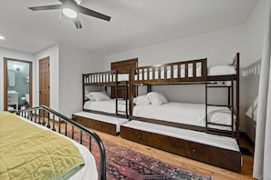 Ein Zimmer mit drei Etagenbetten, einem Deckenventilator und einem Holzschrank.