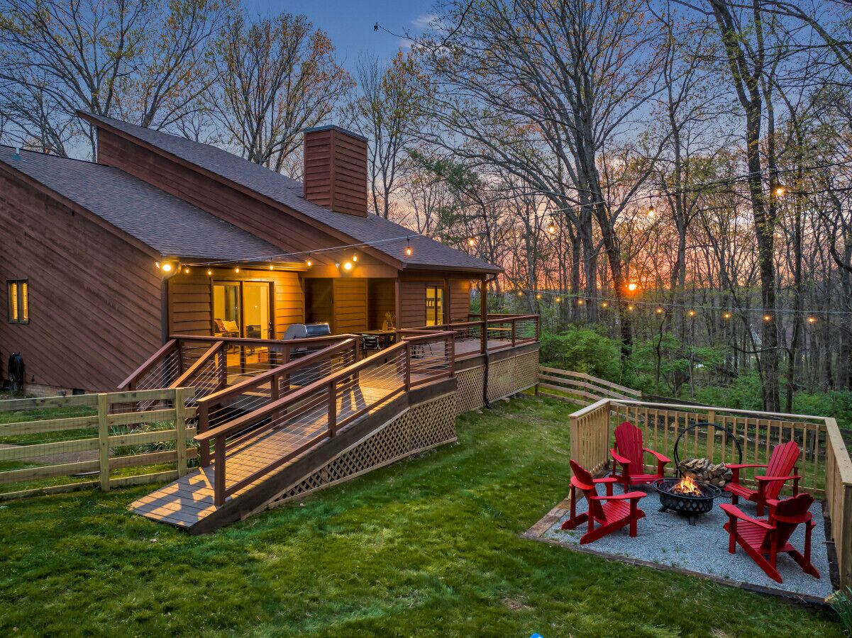 A wooden cabin with a deck, outdoor seating, and a fire pit.