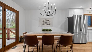 A modern kitchen with a dining area, large windows, and a chandelier.