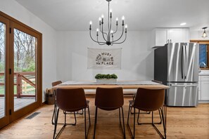 Une cuisine moderne avec un coin repas, de grandes fenêtres et un lustre.