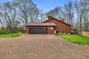 Ein eingeschossiges Holzhaus mit Garage, umgeben von einem gepflegten Rasen und Bäumen.