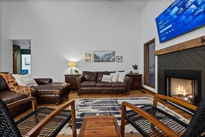 Ein Wohnzimmer mit Kamin, Ledersofas und einem flachbildfernseher an der Wand.