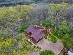 A two-story log cabin with a covered porch and a fenced yard.
