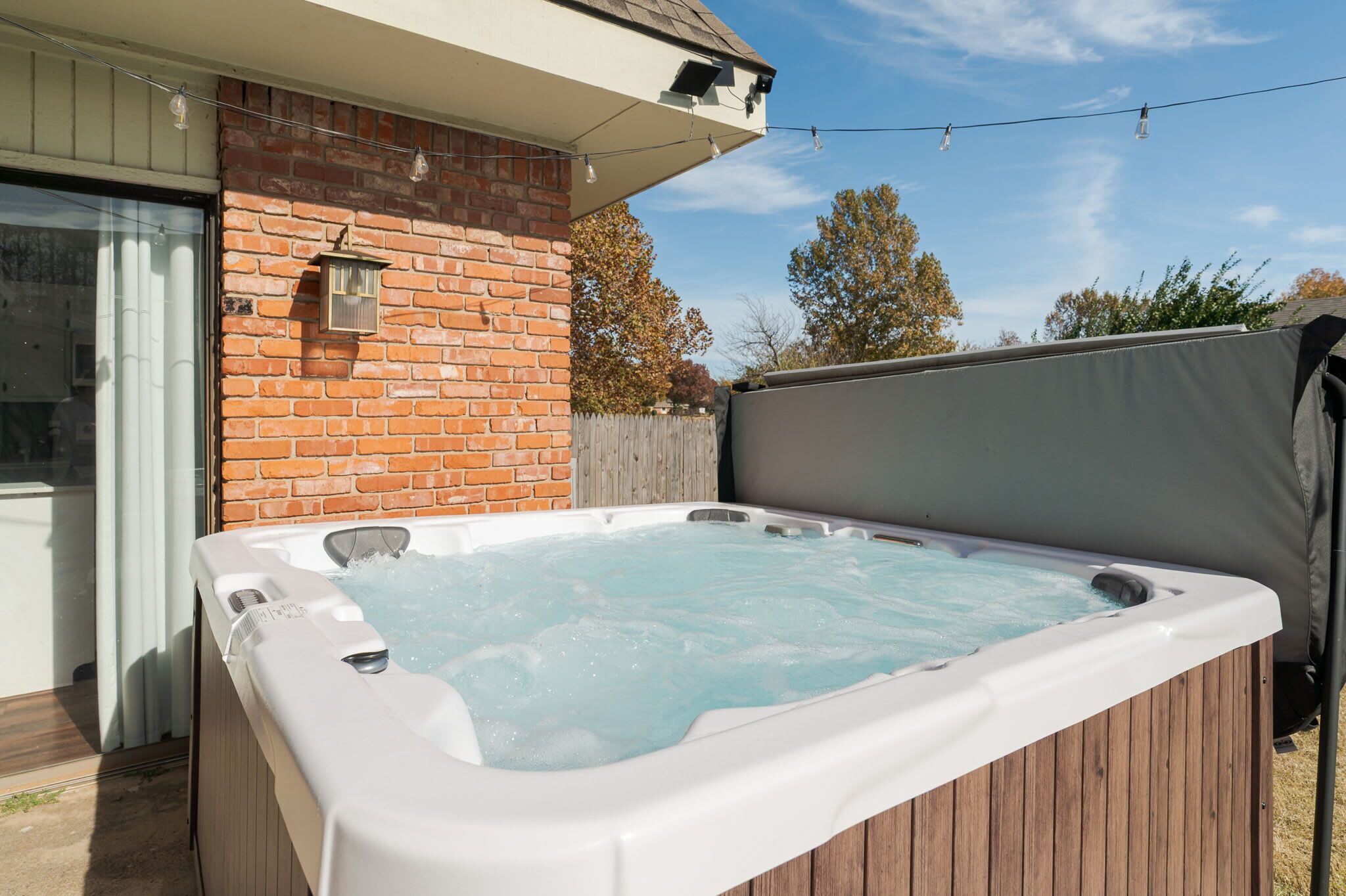 Un bain à remous dans un jardin, avec un mur en briques et une terrasse en bois.