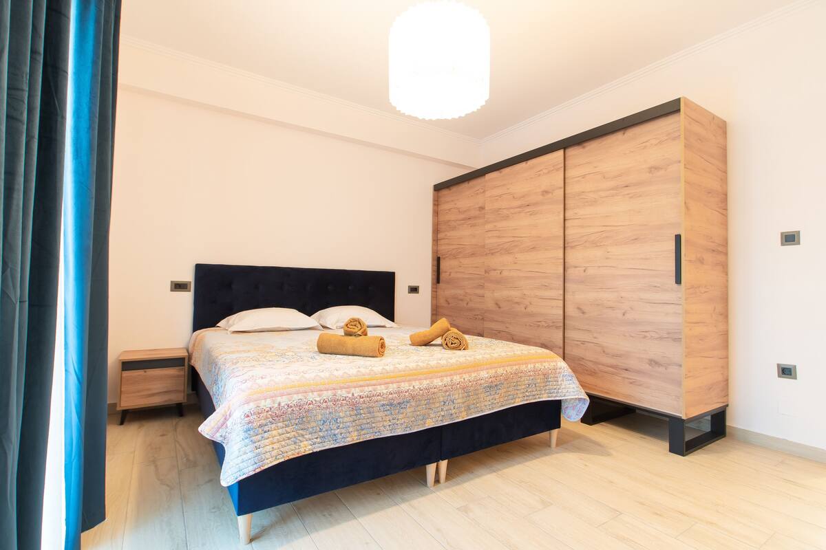 A bedroom with a bed, wooden wardrobe, and a nightstand.