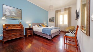 A bedroom with a bed, wooden dresser, chair, and artwork on the walls. - 4BNB - Leone IV Apartment (Rome)