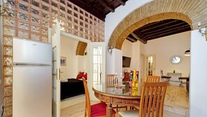A dining area with a glass table, wooden chairs, and a brick archway. - 4BNB - Lungaretta Jacuzzi Apartment (Rome)