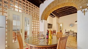 A dining area with a round glass table, wooden chairs, and a glass partition. - 4BNB - Lungaretta Jacuzzi Apartment (Rome)