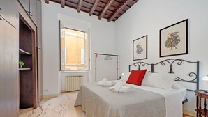 A bedroom with a bed, a window, a radiator, and a wall with framed pictures. - 4BNB - Lungaretta Jacuzzi Apartment (Rome)