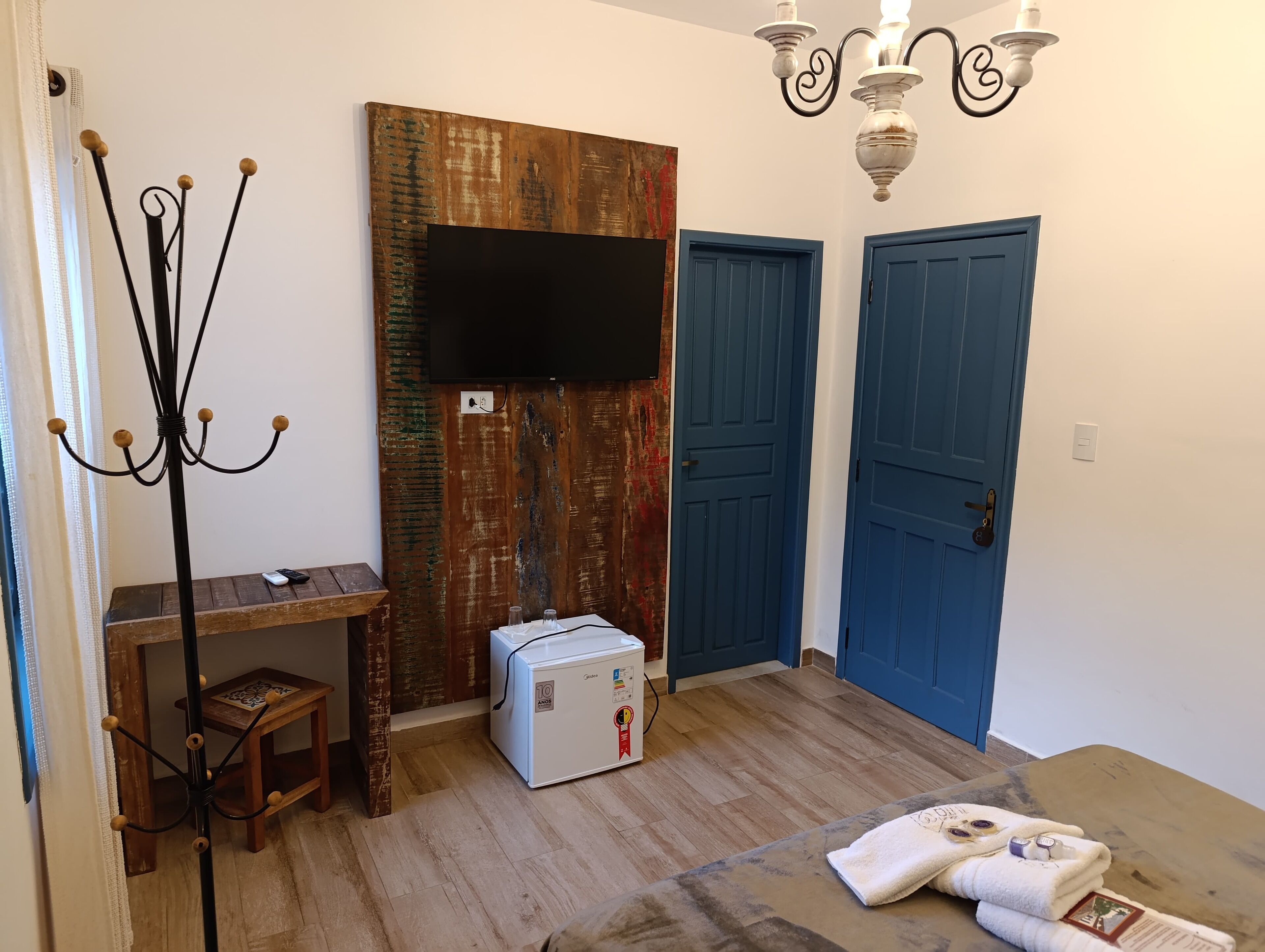 Una stanza con un appendiabiti in legno, un tavolino, un frigorifero bianco e due porte blu.
