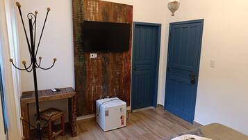 Una stanza con un appendiabiti in legno, un tavolino, un frigorifero bianco e due porte blu.