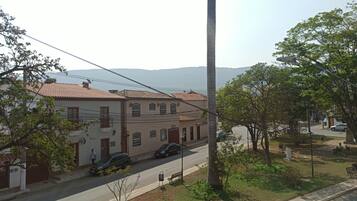 Rua residencial com casas, uma palmeira e vista clara de montanhas ao longe.