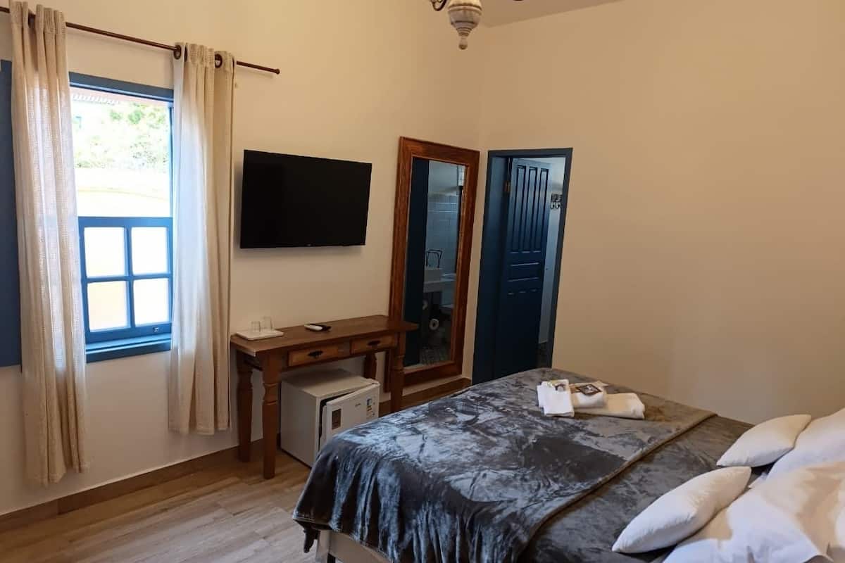 A bedroom with a bed, a desk, a television, and a wardrobe.