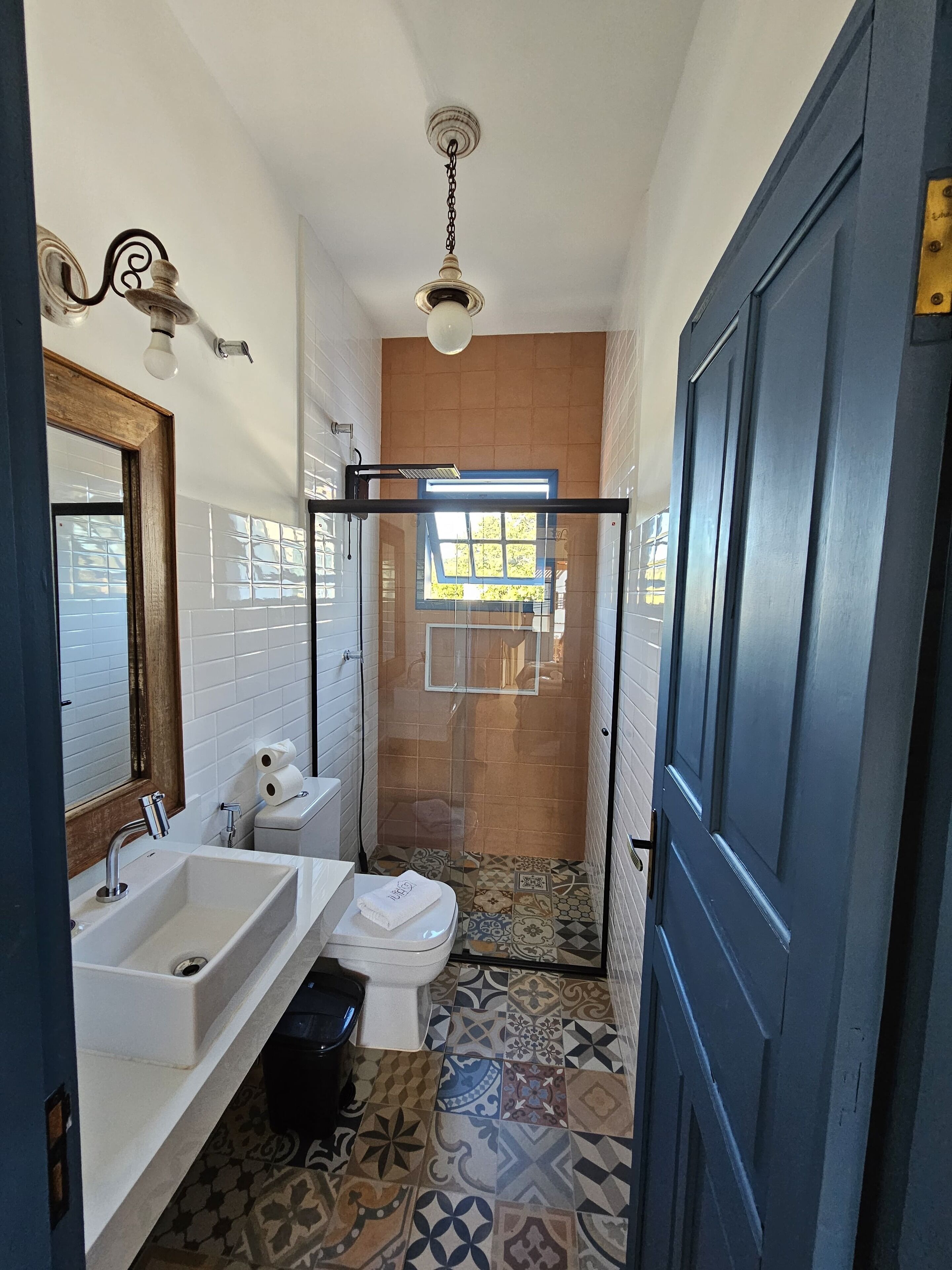 Un bagno compatto con lavandino, water e doccia bianchi.