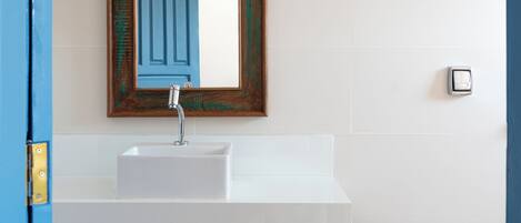 A bathroom with a white sink, a wooden-framed mirror, and a patterned tile floor.