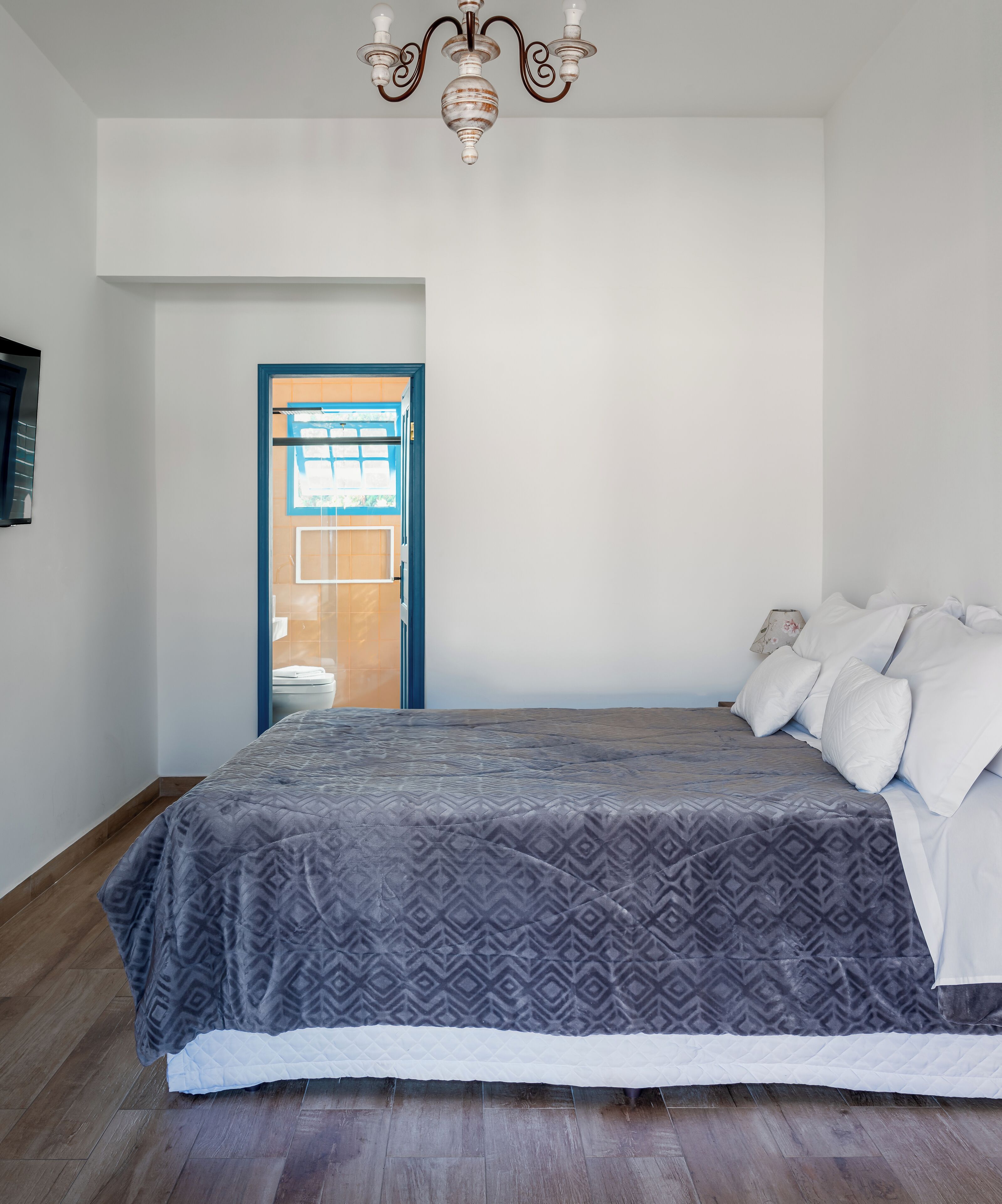 Un dormitorio con cama, candelabro, puerta y vista al exterior.