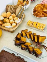 A variety of baked goods including bread, rolls, and a cake with chocolate glaze.