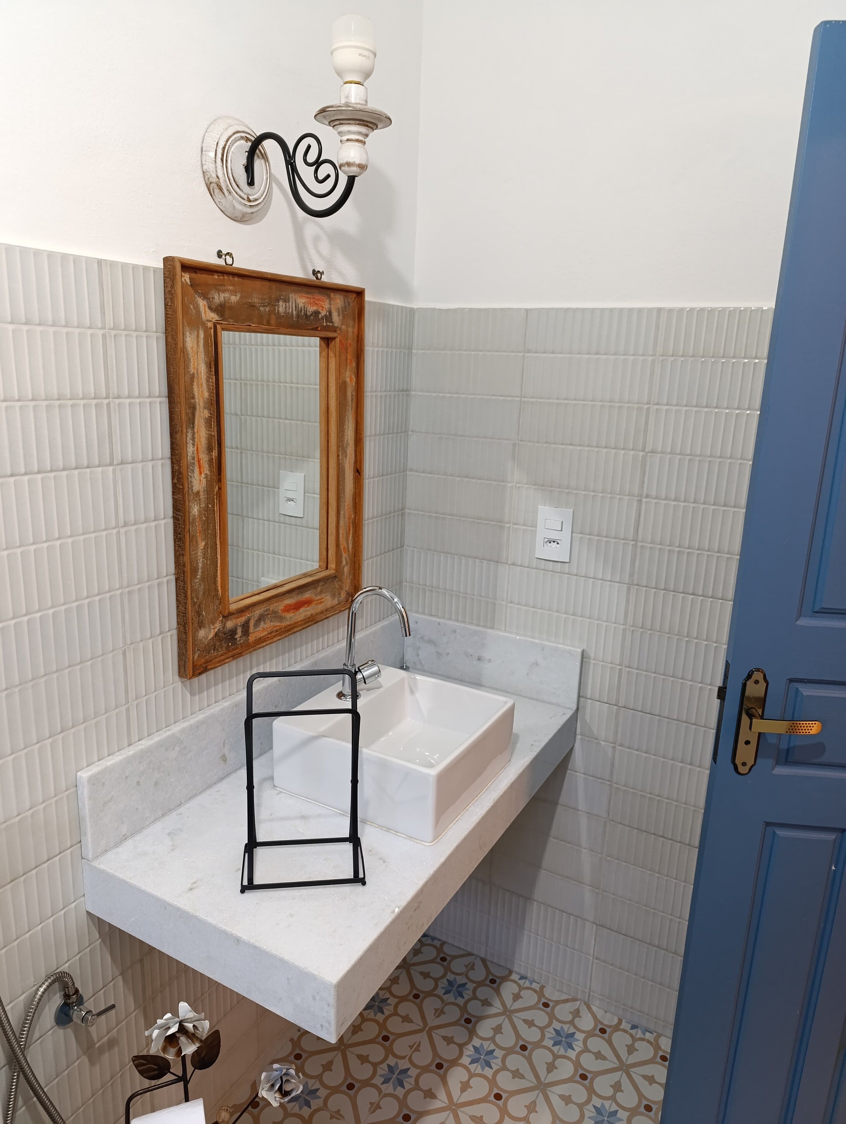 A bathroom with a white sink, a mirror with a wooden frame, a towel rack, and a light fixture.