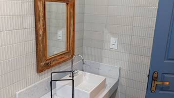 A bathroom with a white sink, a mirror with a wooden frame, a towel rack, and a light fixture.