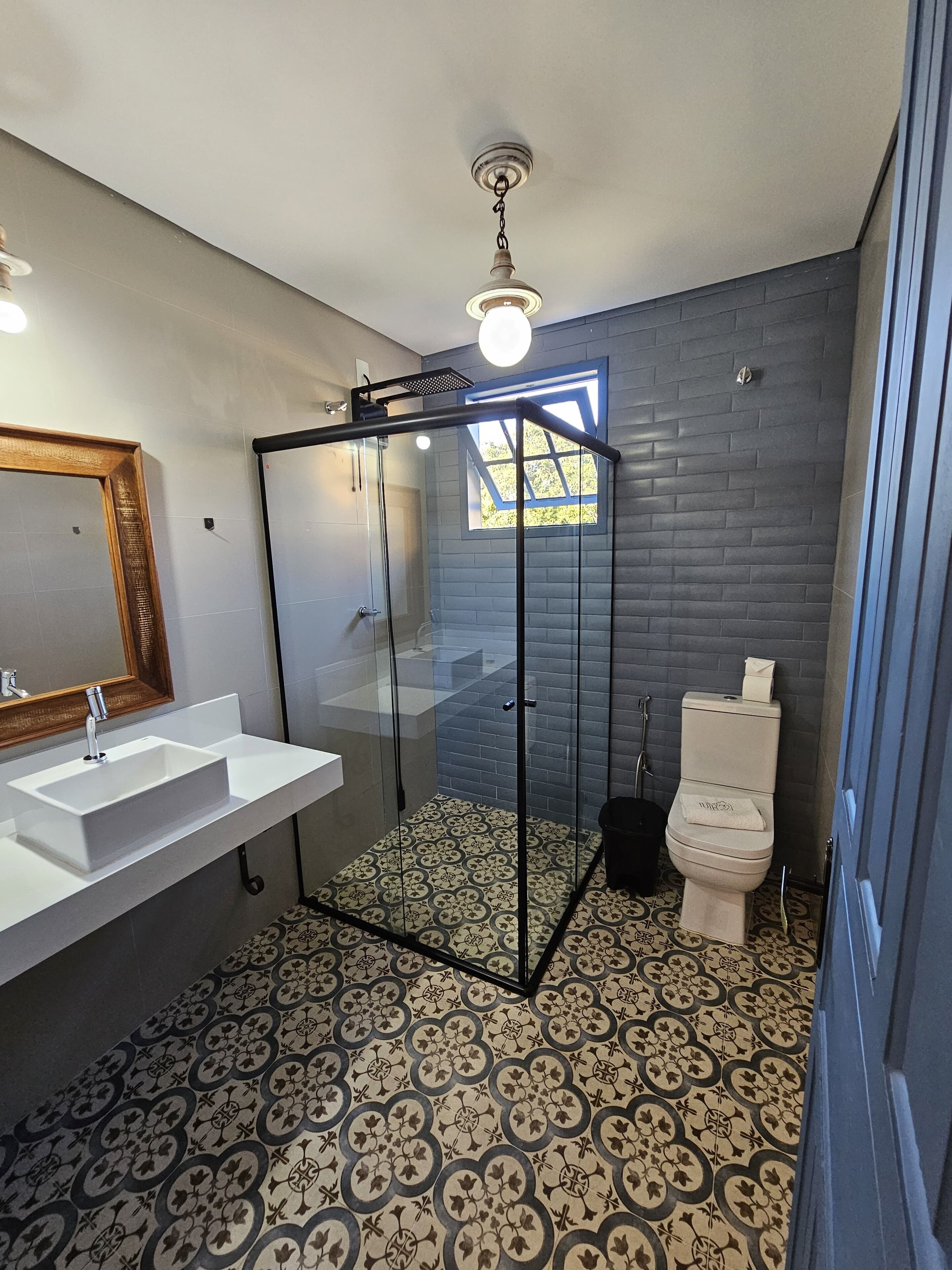 A modern bathroom with a glass-enclosed shower, a white sink with a mirror, and a toilet.