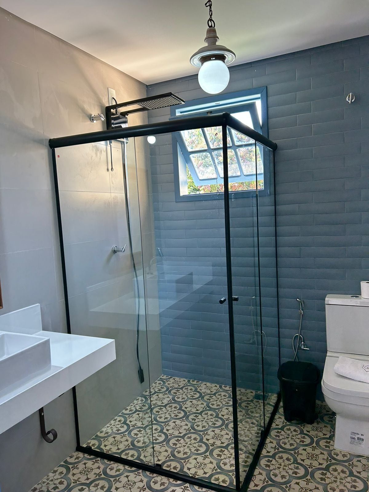 Un baño moderno con cabina de ducha de vidrio, un lavabo blanco y un inodoro.
