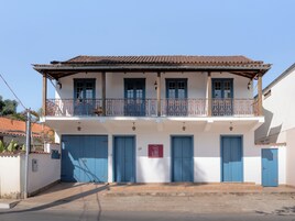 A two-story building with blue doors and a balcony with decorative iron railings.