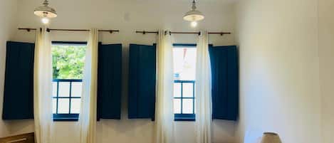 Una habitación con una cama, un escritorio y dos ventanas con cortinas.