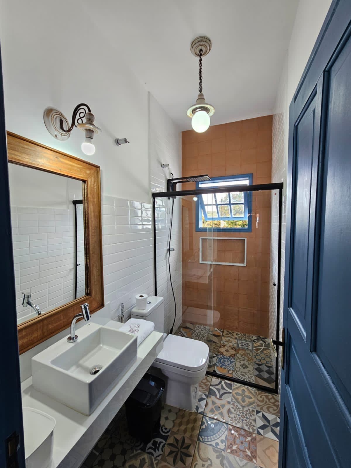 A bathroom with a white sink, a mirror, a toilet, and a shower area.