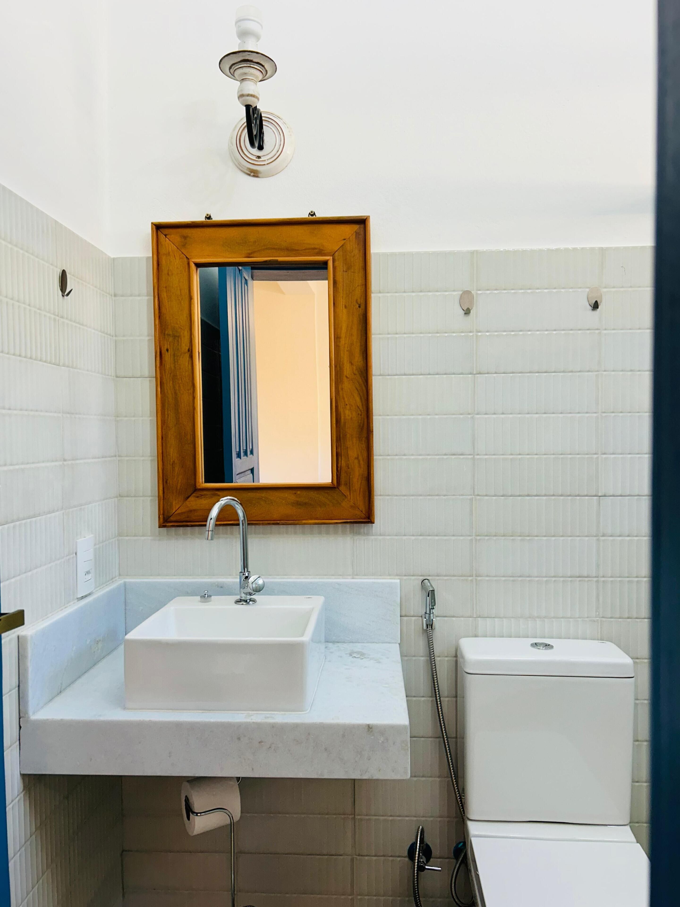 A bathroom with a white sink, a wooden-framed mirror, and a white toilet.