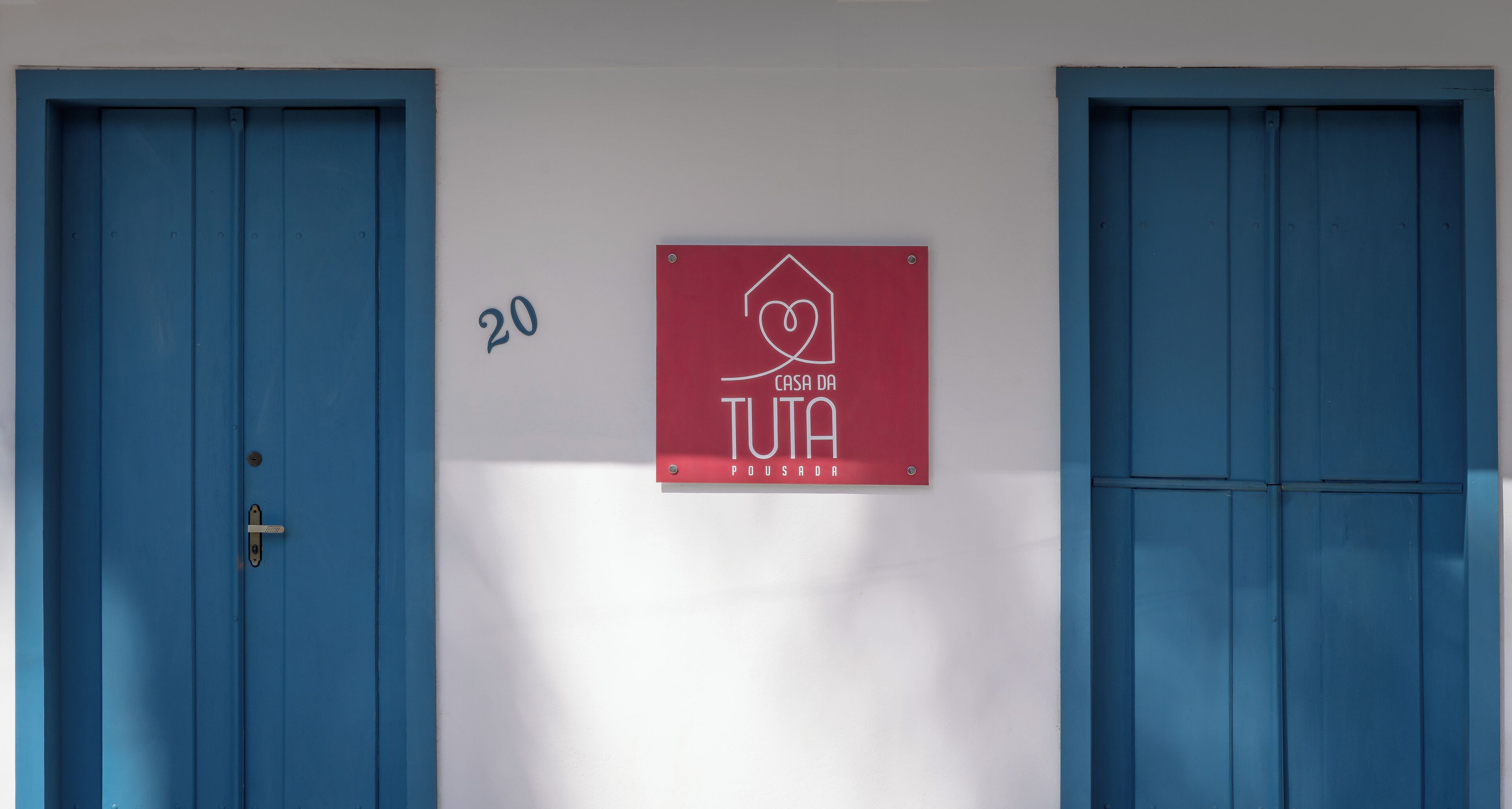 A building with two blue doors and a red sign with a heart and house symbol, indicating a possible lodging or care facility.