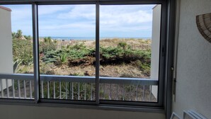 A room with a large window overlooking a beach and dunes. - Appartement Avec vue Mer à Marseillan Plage (Marseillan)