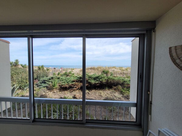 Una habitación con un ventanal grande que da a una playa y dunas.
