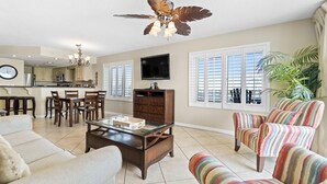 A spacious living room with a ceiling fan, a television, and a dining area with wooden furniture.