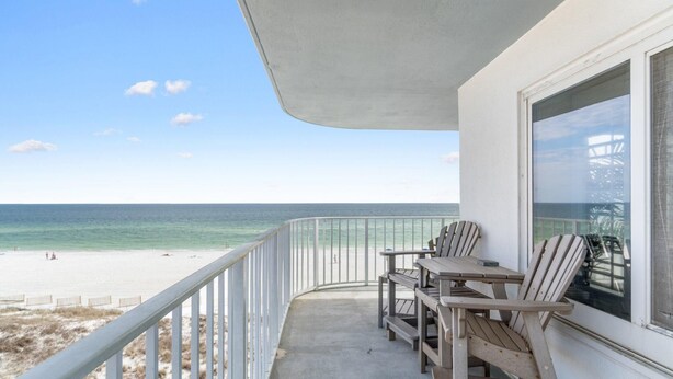 A balcony with a view of the beach and ocean.